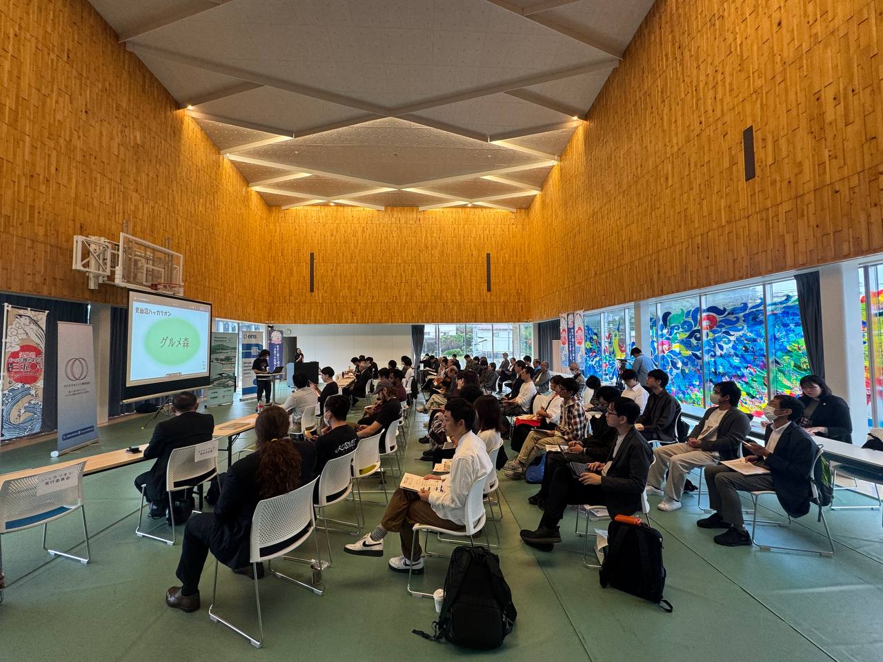 Full audience view with geometric ceiling design